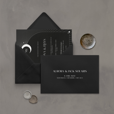 Wedding stationery flatlay with printed address on a black envelope designed by The Little Paper Shop