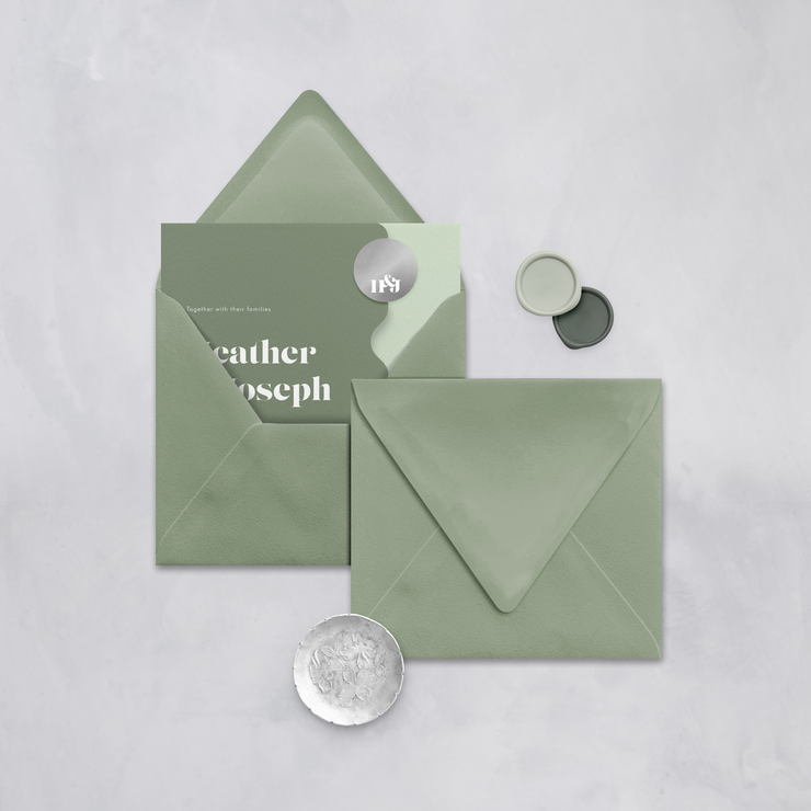 Wedding stationery flatlay with invitation inside a sage green envelope designed by The Little Paper Shop