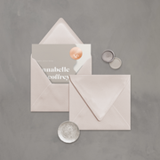 Wedding stationery flatlay with invitation inside a neutral coloured envelope designed by The Little Paper Shop