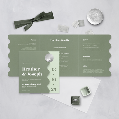 Green Wedding stationery flatlay with wavy edge designed by The Little Paper Shop