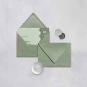 Wedding stationery flatlay with invitation inside a sage green envelope designed by The Little Paper Shop