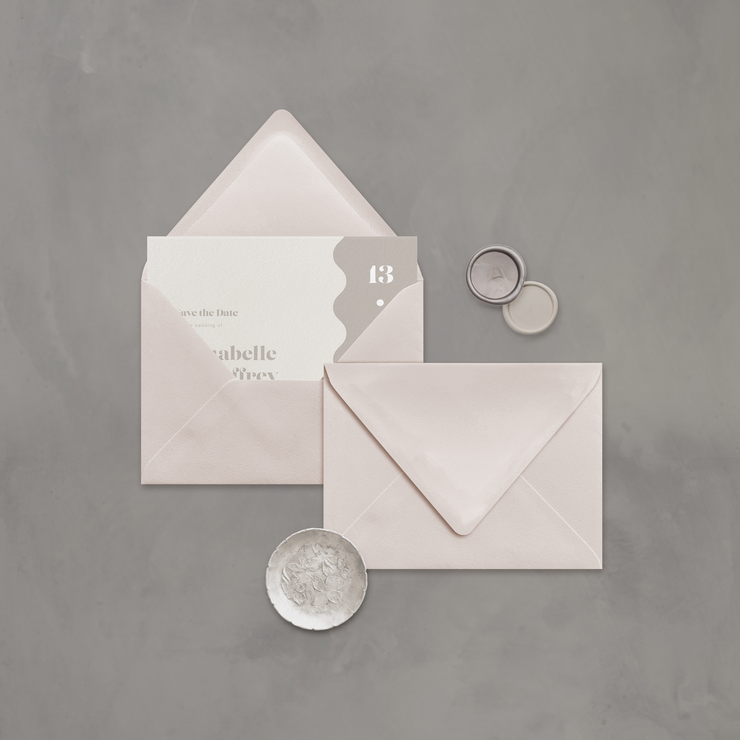Wedding stationery flatlay with invitation inside a neutral coloured envelope designed by The Little Paper Shop