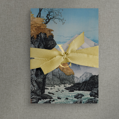 Mountains wedding invitation wrapped with gold silk tie with a bow to the front, designed by The Little Paper Shop